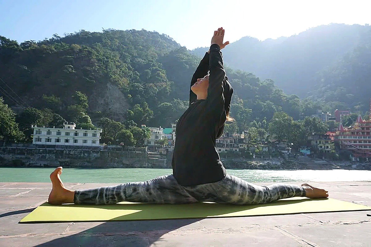 Student practicing a backbend pose on a riverside terrace