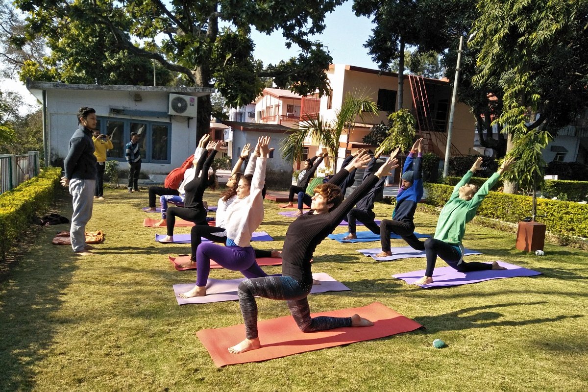 Beginner practicing a low lunge pose during an outdoor yoga session in Rishikesh