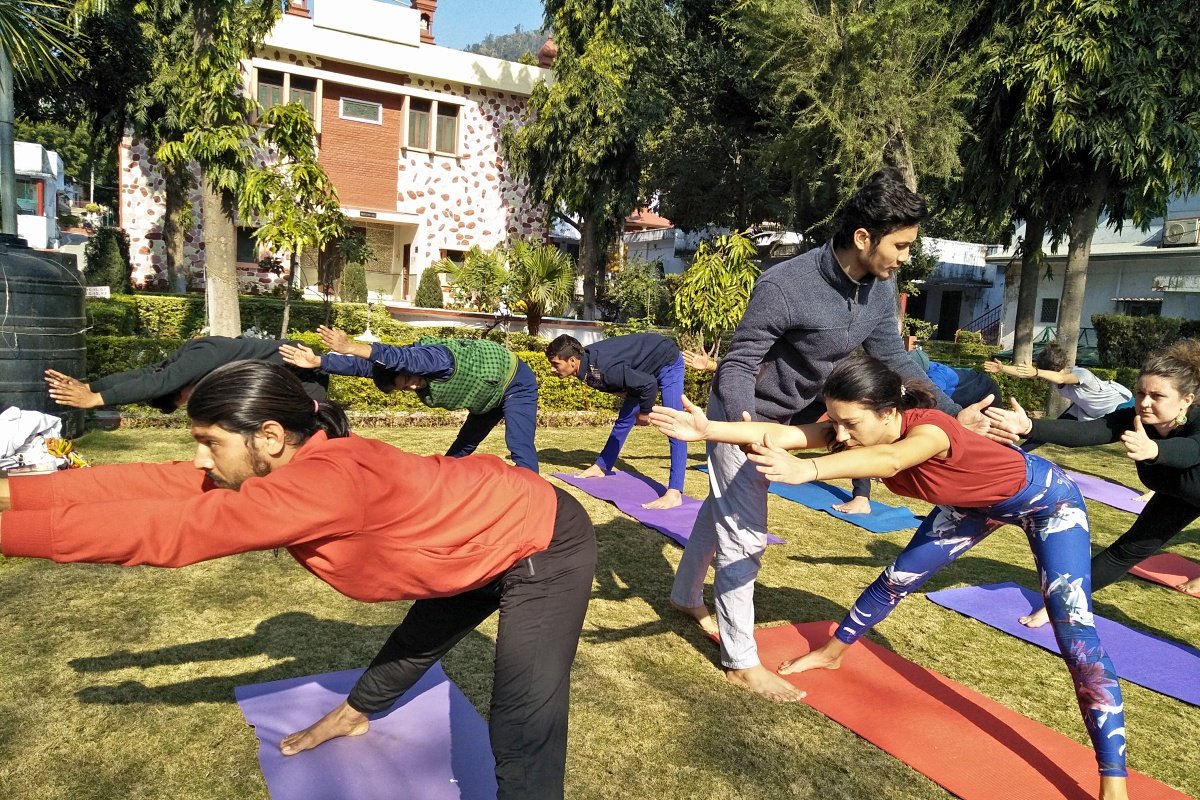 Teacher adjusting a student's warrior pose during an outdoor class