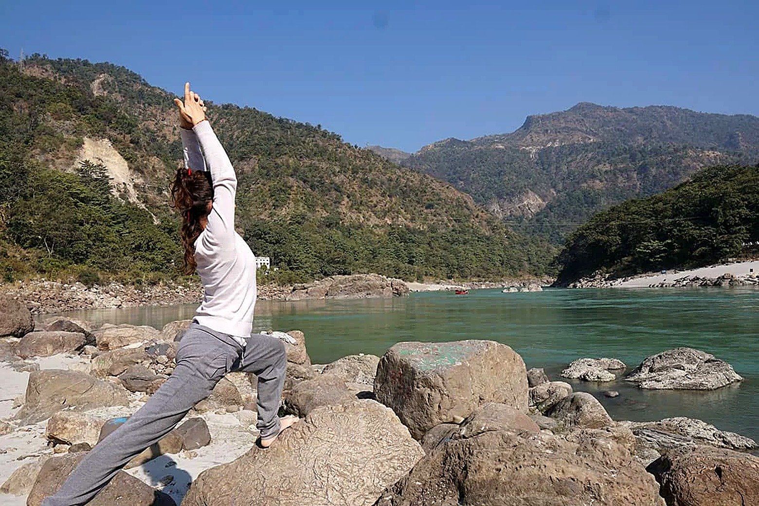 Warrior pose practice on the riverside rocks in Rishikesh